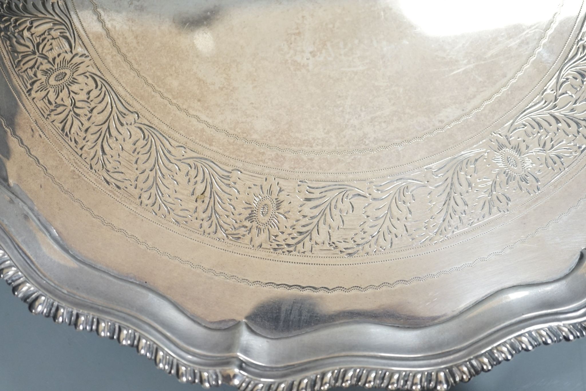 A George III silver salver, with gadrooned border, on three shell feet, Ebenezer Coker, London, 1773, 28.1cm, (repairs), 20.5oz.